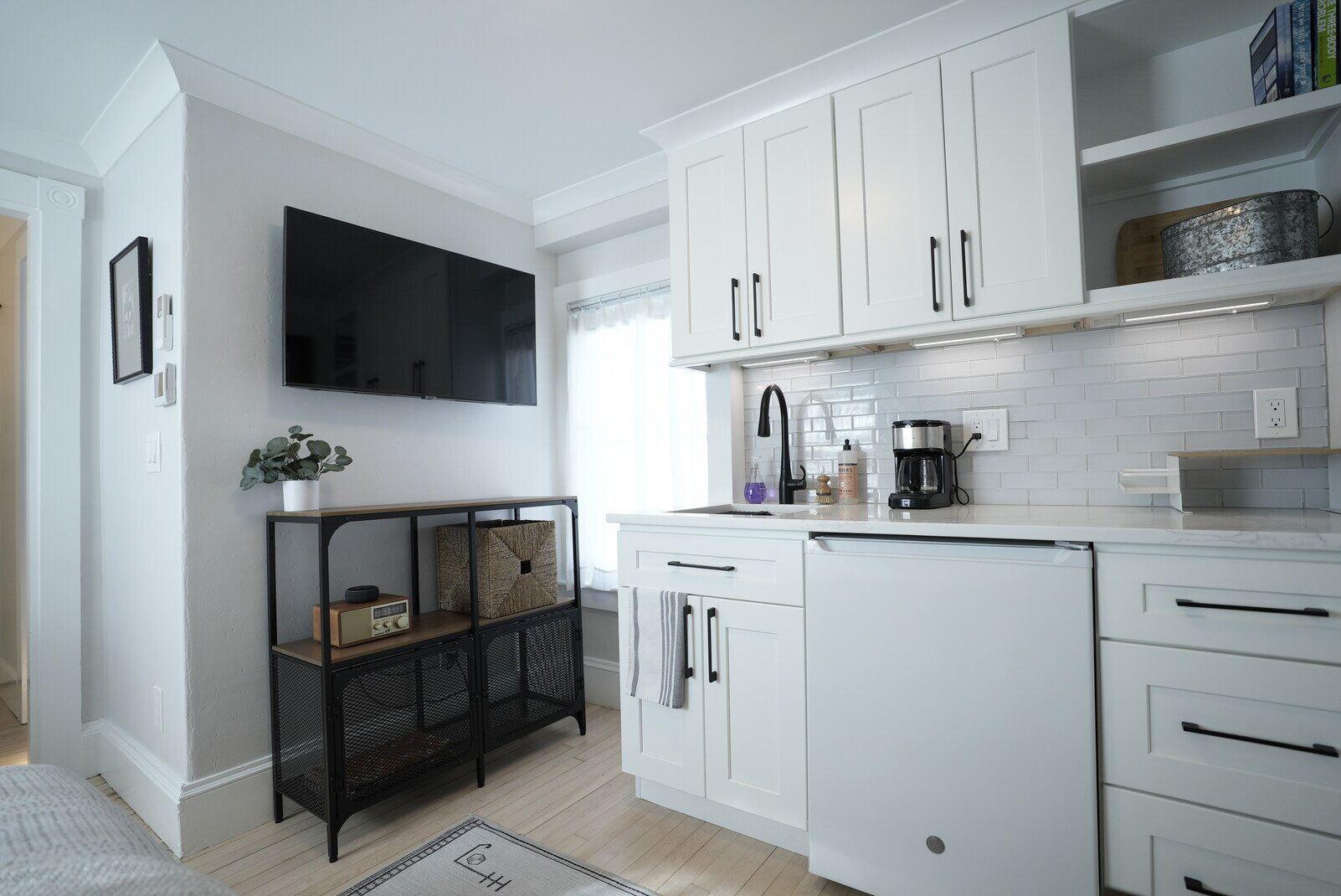 Modern kitchen with white cabinetry and TV, part of a kitchen remodel by Oxland Builders in New Hampshire