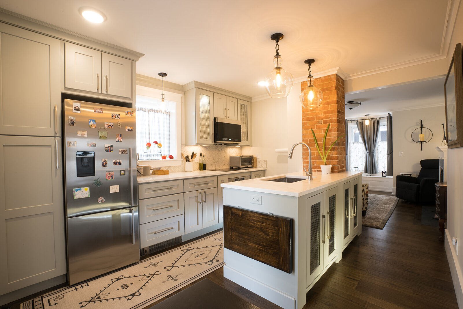 Spacious kitchen with an island, stainless steel appliances, and brick accent wall, remodeled by Oxland Builders in New Hampshire